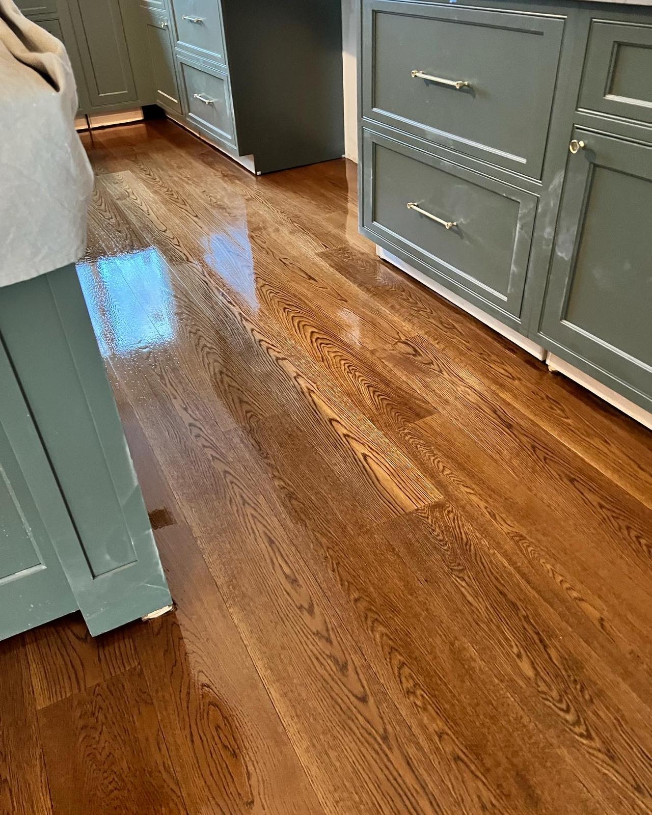 Refinished hardwood floor in a kitchen with green cabinetry