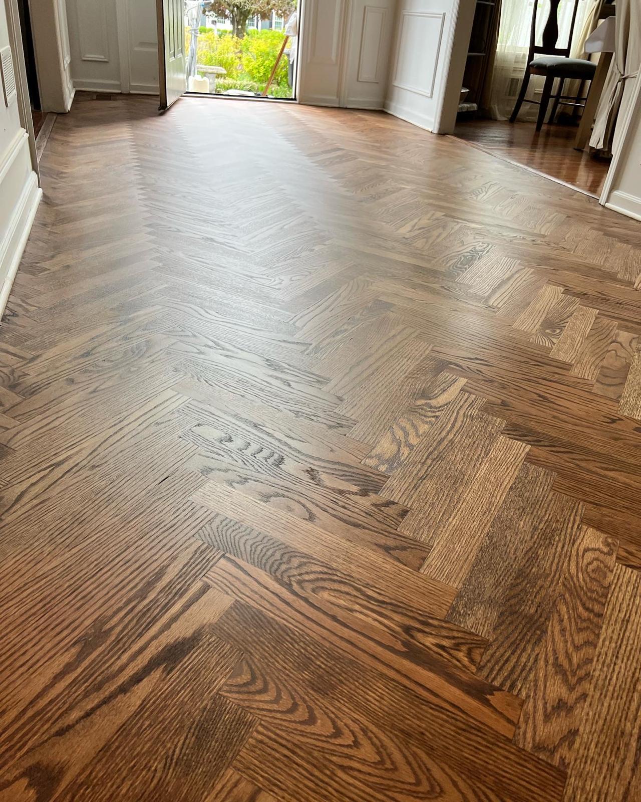 Herringbone hardwood floor in an entryway with a staircase